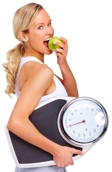 Young woman eating apple and carrying a weight scale over white background